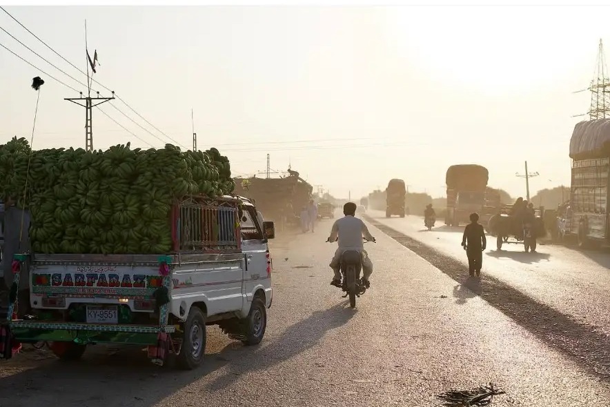 Truck loaded with green bananas on a dusty backlit road in Hyderabad, Sindh, Pakistan