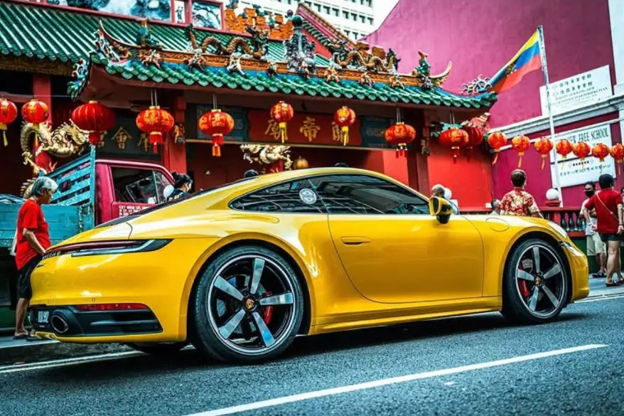 Yellow sports car passing the red Sin Sze Si Ya Temple