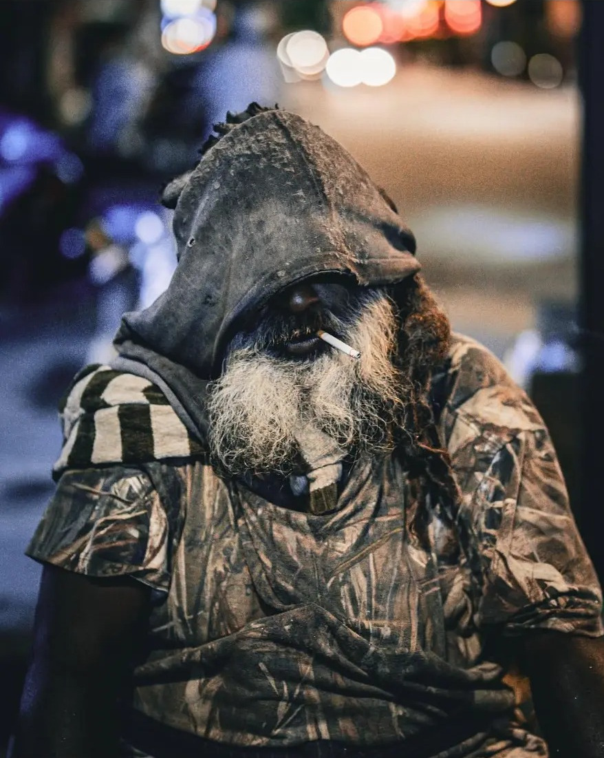 Portrait of an elderly man in a hood smoking at night on Jalan Petaling