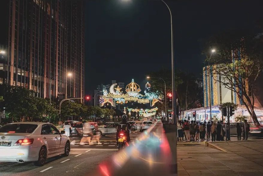 Street decorated with festive lights at night with passing traffic