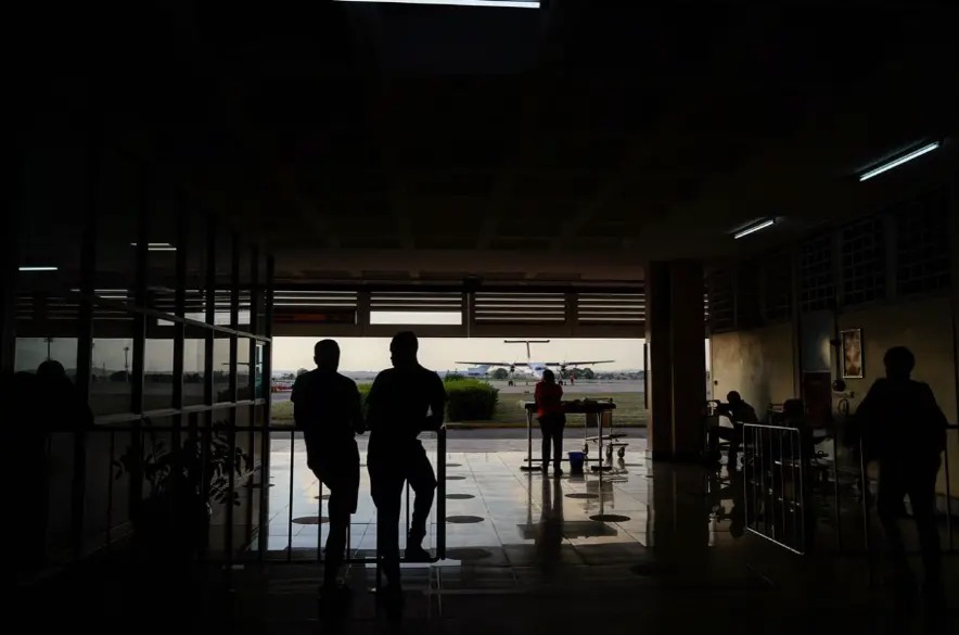 Travellers silhouetted in the terminal doorway while a plane refuels at Mombasa airport, Kenya