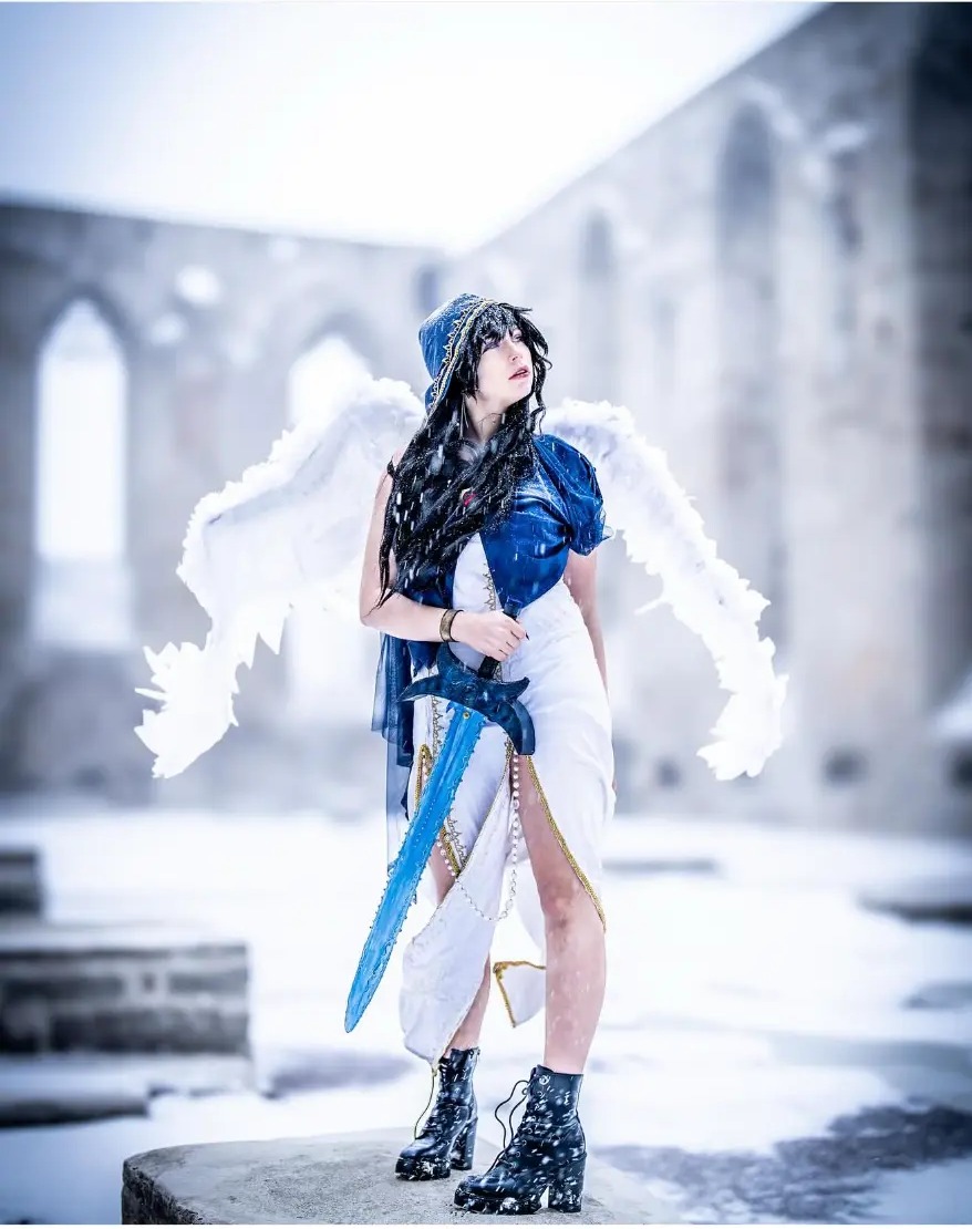 Cosplay portrait with white wings and a blue sword in the snow at Pirita Convent, Tallinn, Estonia