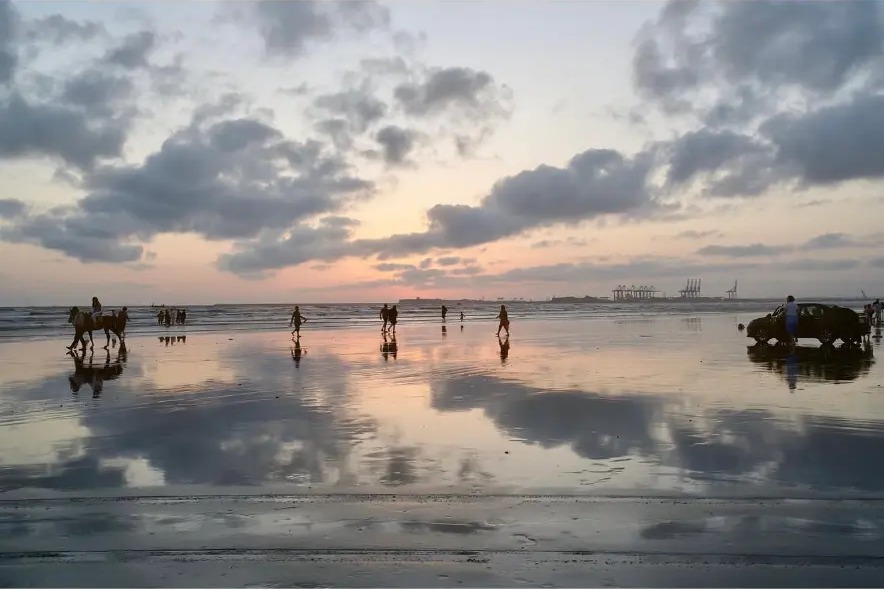 Clouds reflected in the wet sand at sunset on the beach in Karachi, Pakistan