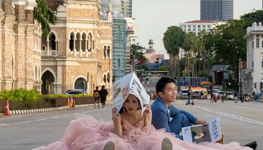 Couple in a pink gown and blue suit posing on the road at a wedding shoot on Merdeka Square