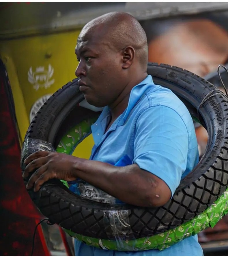 Man carrying a motorbike tyre over his shoulder on Tom Mboya Street in Nairobi, Kenya