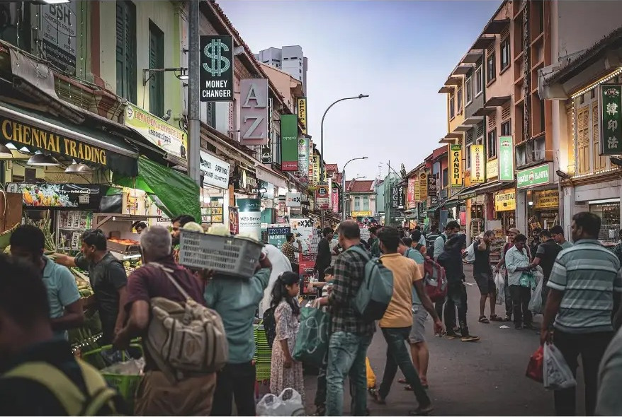 Crowded market street lined with shop signs at dusk