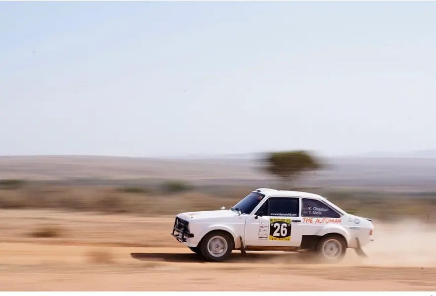 White rally car number 26 sliding through desert dust
