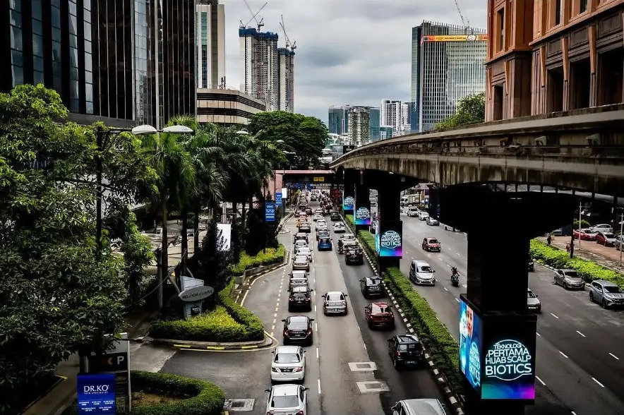 Traffic flowing past Berjaya Times Square under grey skies in Kuala Lumpur, Malaysia