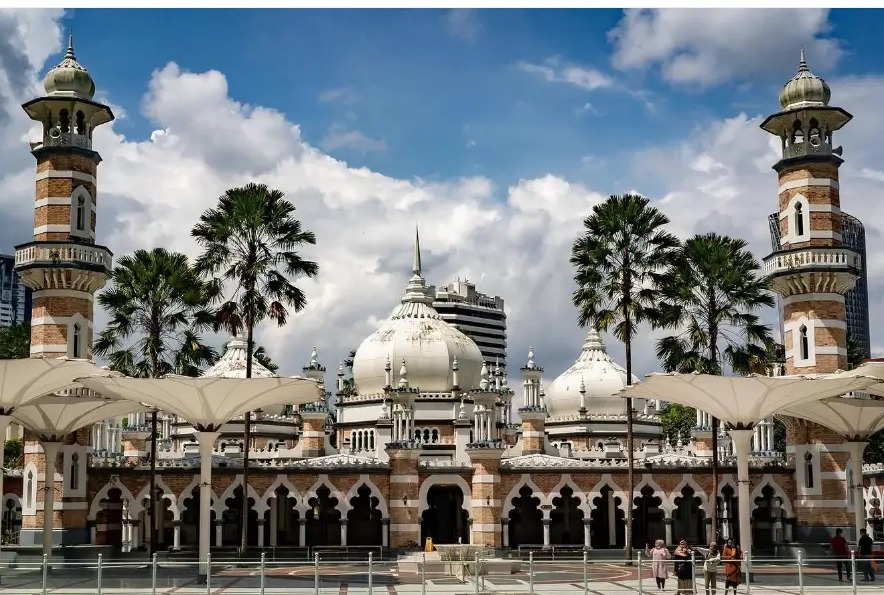 Masjid Jamek Sultan Abdul Samad with palm trees under bright clouds in Kuala Lumpur, Malaysia