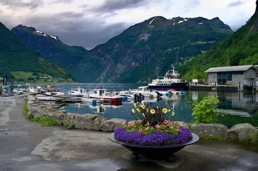 Boats moored in a fjord harbour below steep green mountains