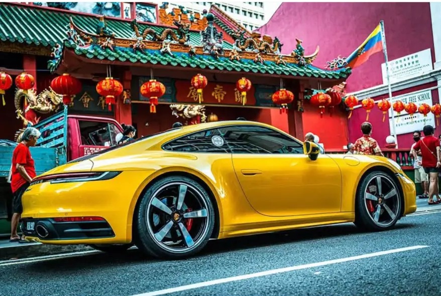 Yellow sports car passing the red Sin Sze Si Ya Temple