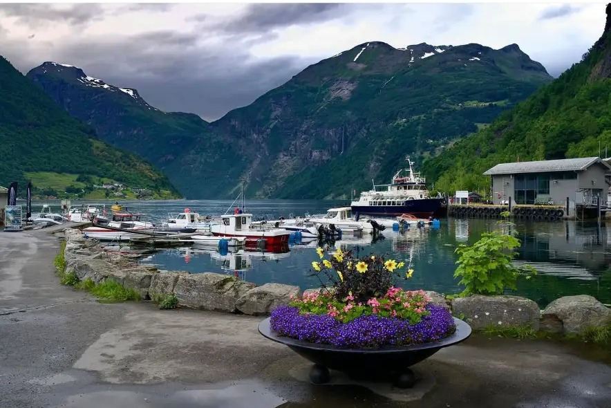 Boats moored in a fjord harbour below steep green mountains