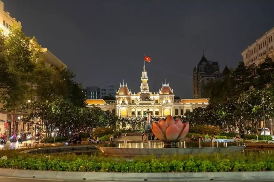 Ho Chi Minh City Hall lit up at night above a lotus fountain