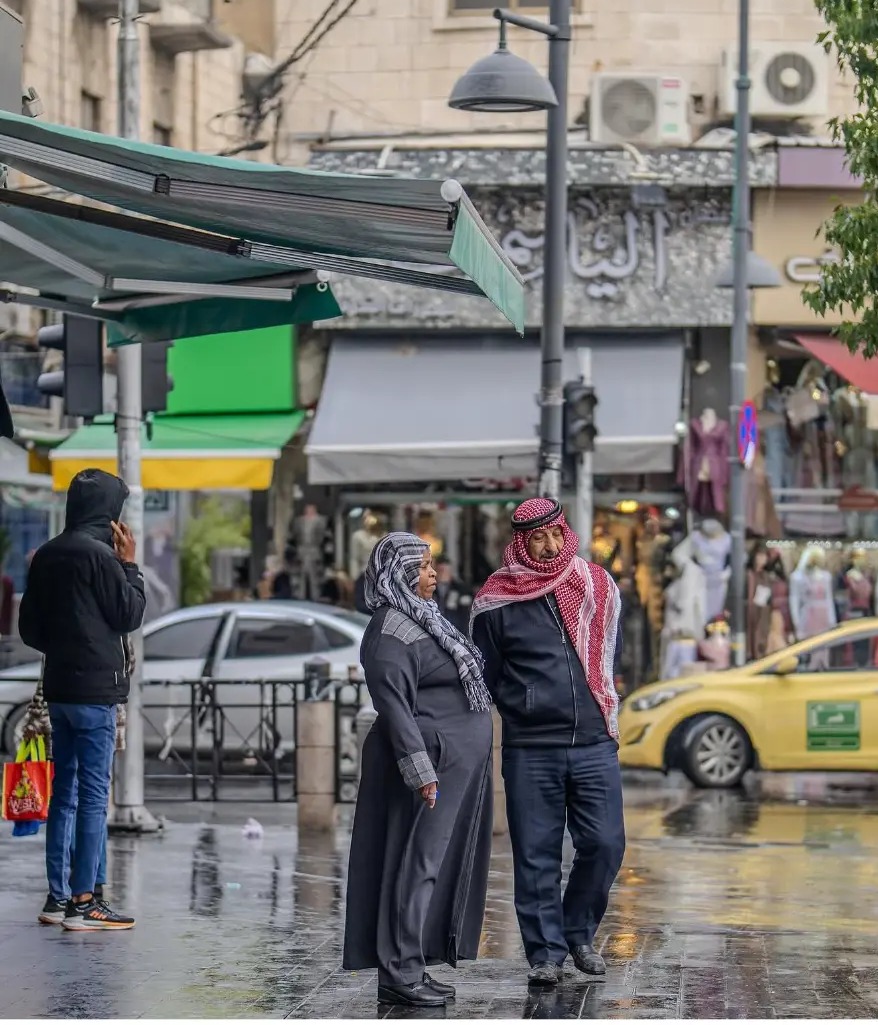 Couple crossing a wet downtown street after rain in Amman, Jordan