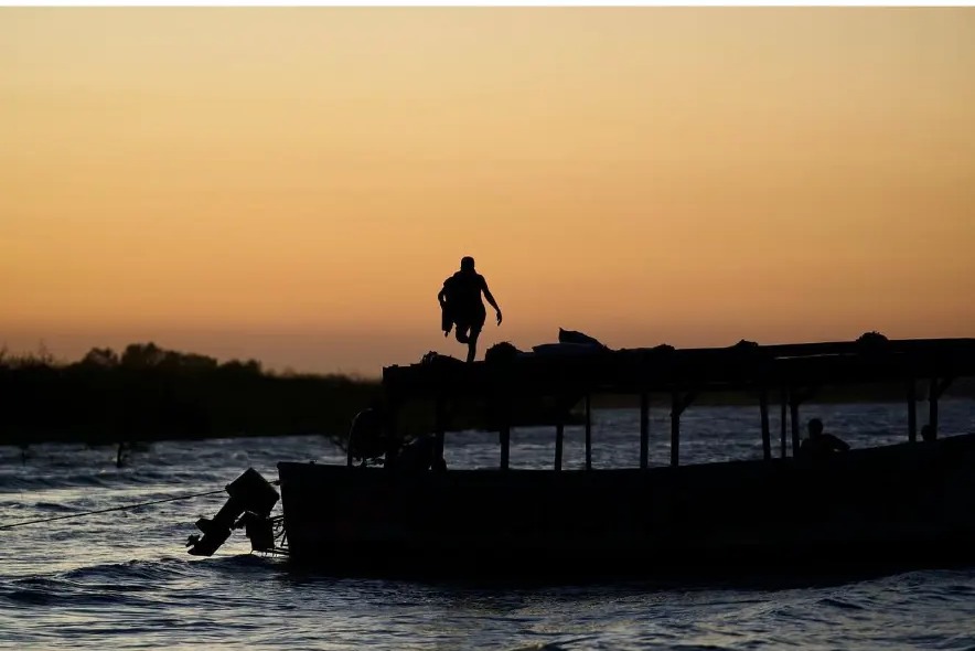 Silhouette of a man jumping onto a boat at sunset on Lake Malawi