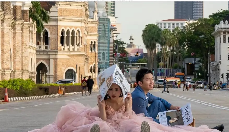 Couple in a pink gown and blue suit posing on the road at a wedding shoot on Merdeka Square