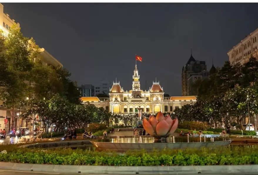 Ho Chi Minh City Hall lit up at night above a lotus fountain