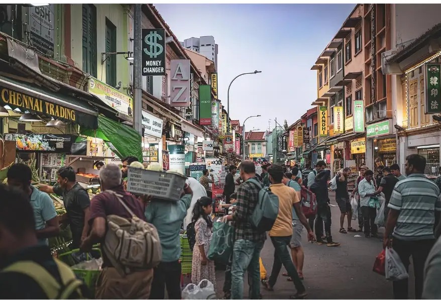 Crowded market street lined with shop signs at dusk