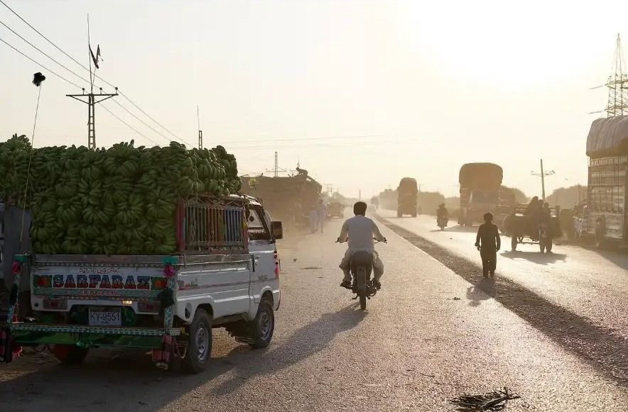 Truck loaded with green bananas on a dusty backlit road in Hyderabad, Sindh, Pakistan