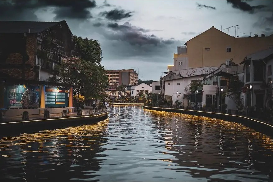 Malacca River at dusk with golden lights reflected on the water