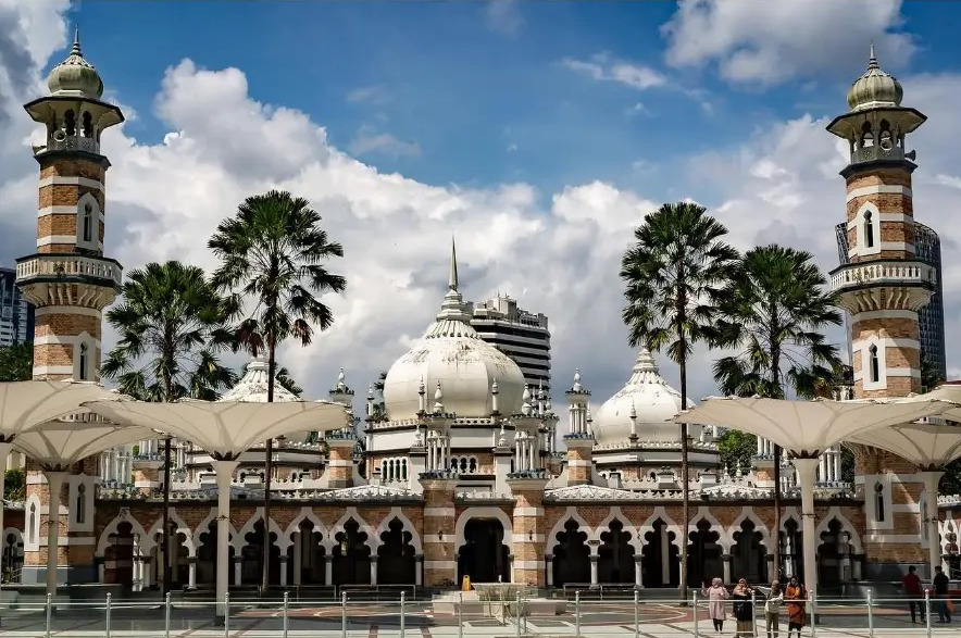Masjid Jamek Sultan Abdul Samad with palm trees under bright clouds in Kuala Lumpur, Malaysia