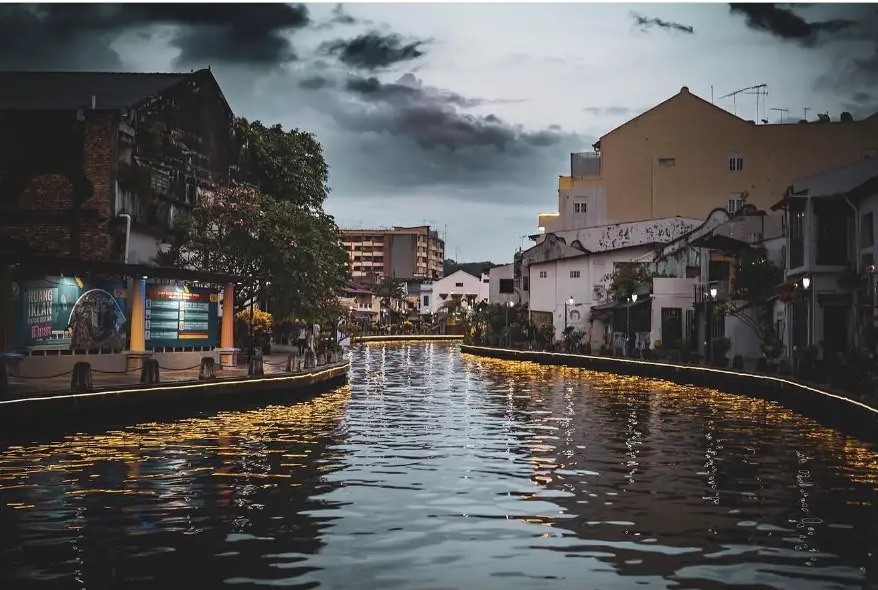 Malacca River at dusk with golden lights reflected on the water