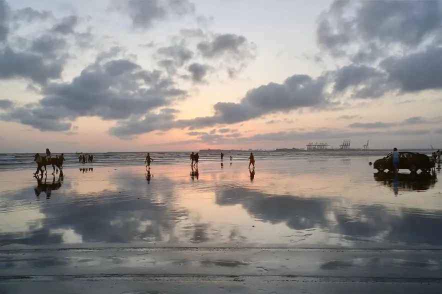 Clouds reflected in the wet sand at sunset on the beach in Karachi, Pakistan
