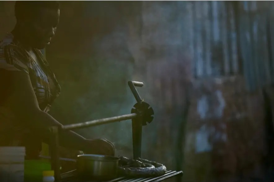 Street food cook working at a low stove in soft window light