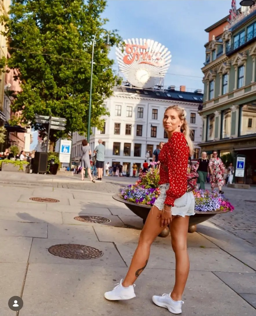 Woman in a red blouse walking past flower planters on Karl Johans gate in Oslo, Norway