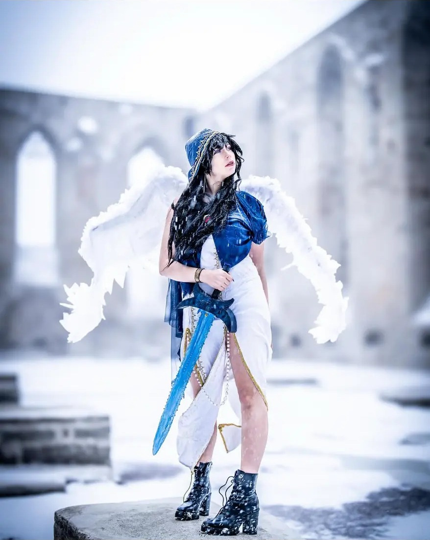 Cosplay portrait with white wings and a blue sword in the snow at Pirita Convent, Tallinn, Estonia