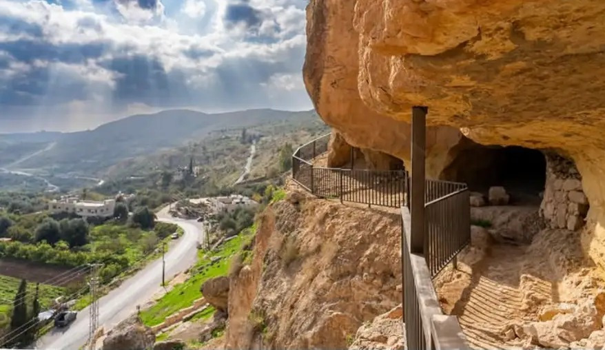Cliffside caves above the green Wadi Seer valley at Iraq Al-Amir, Jordan