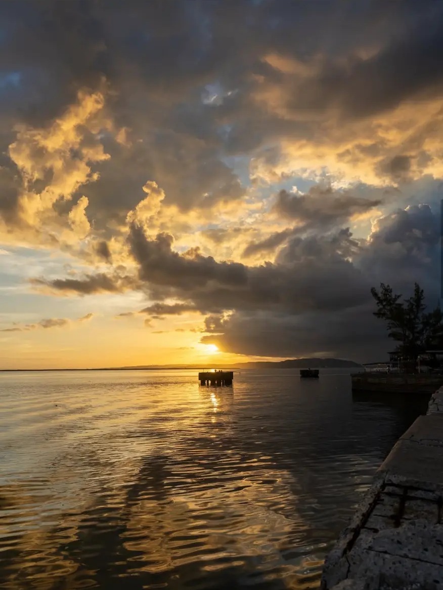 Golden sunset over calm water with a jetty in Kingston, Jamaica