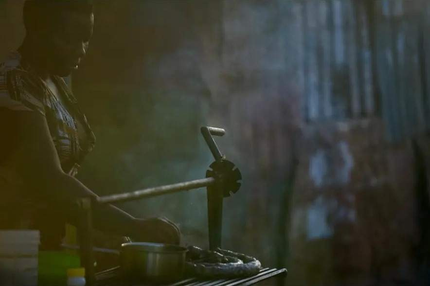 Street food cook working at a low stove in soft window light