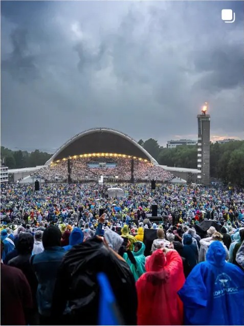 Huge crowd in rain ponchos in front of the song festival stage