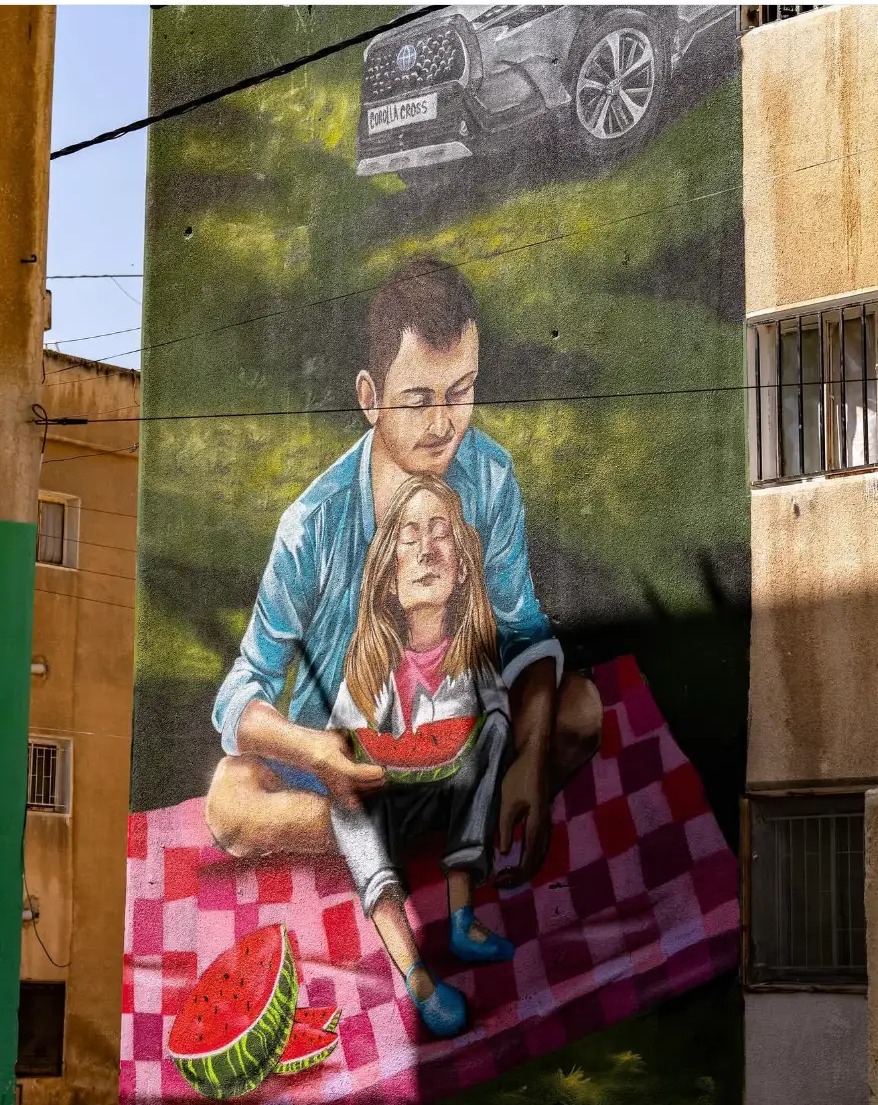 Mural of a man and child sharing watermelon on a building wall in Amman, Jordan