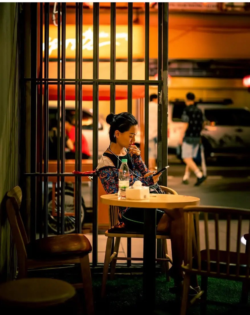 Woman sitting alone at a dessert shop table at night