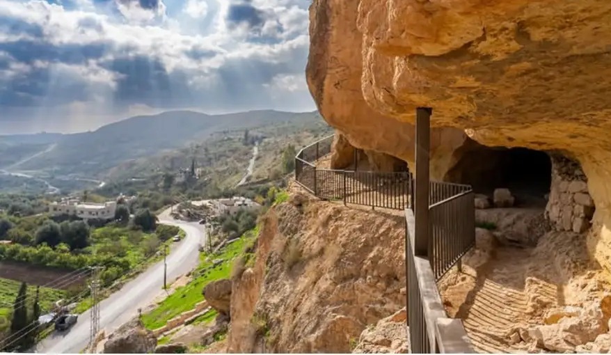 Cliffside caves above the green Wadi Seer valley at Iraq Al-Amir, Jordan