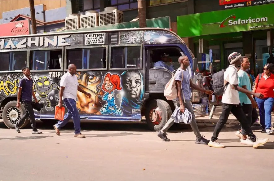 Graffiti-covered matatu bus and pedestrians on Tom Mboya Street, Nairobi, Kenya