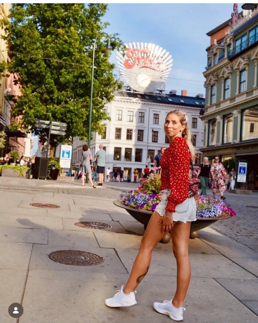 Woman in a red blouse walking past flower planters on Karl Johans gate in Oslo, Norway