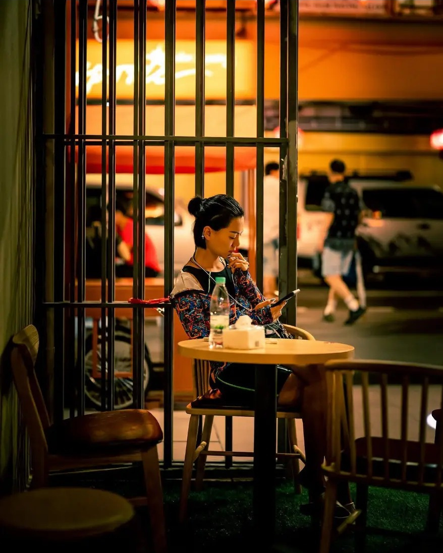 Woman sitting alone at a dessert shop table at night