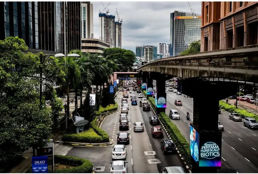 Traffic flowing past Berjaya Times Square under grey skies in Kuala Lumpur, Malaysia