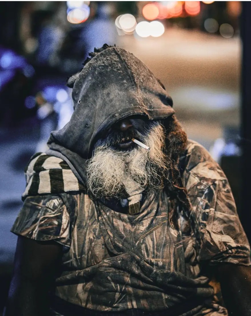 Portrait of an elderly man in a hood smoking at night on Jalan Petaling