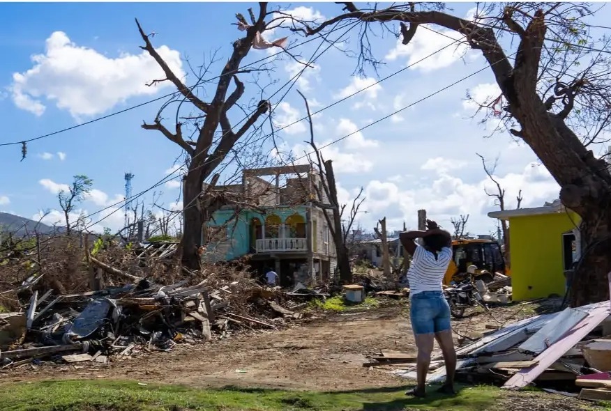 Woman standing among storm debris after Hurricane Melissa in St Elizabeth, Jamaica