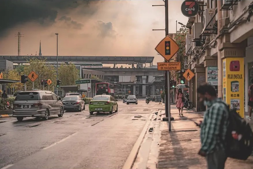 Wet street with traffic signs and passers-by under a sunset sky